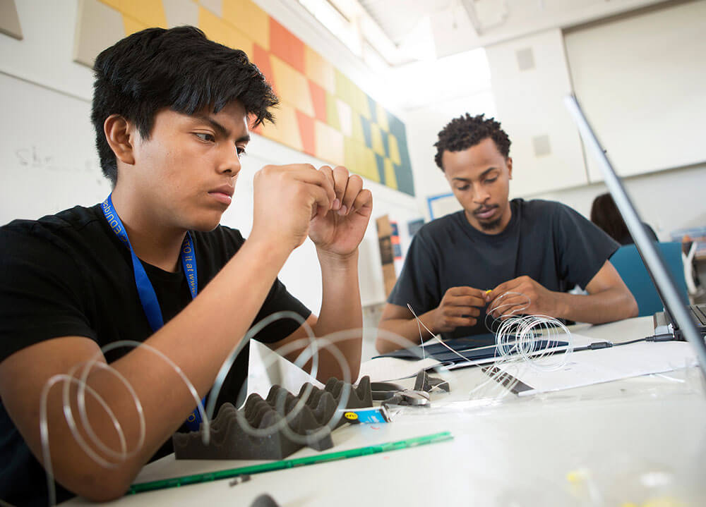 A local high school student works with a Quinnipiac student on a project in the Center for Innovation and Entrepreneurship