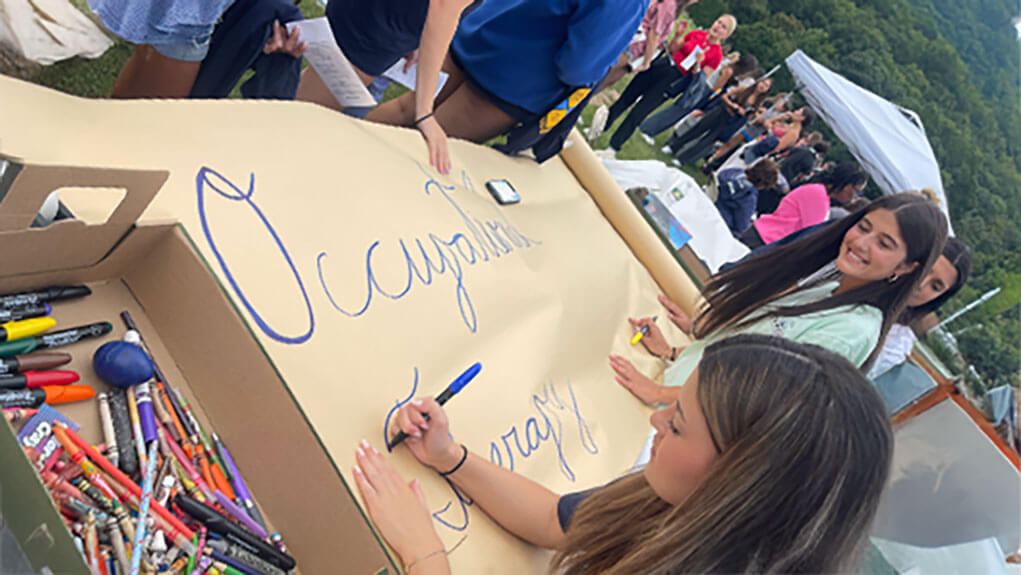 Students drawing on a banner for living learning community event