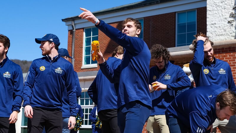 Men's ice hockey team players toss rolled up tee shirts to the crowd