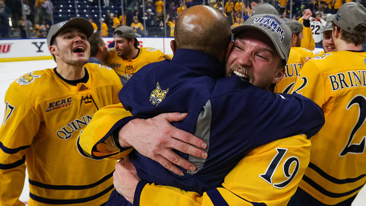 Men's Ice Hockey group hugs on the ice after a goal