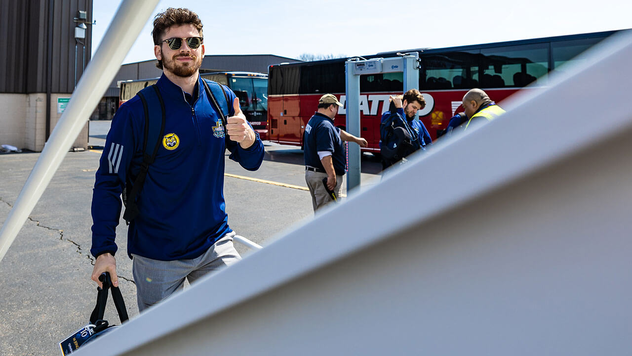 A member of the men's ice hockey team boards a Tampa-bound plane.