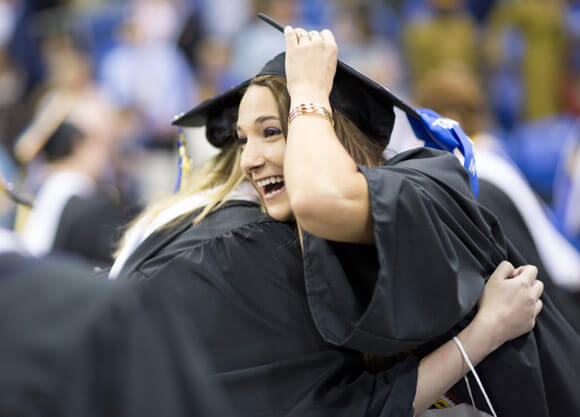 Two students hugging at commencement