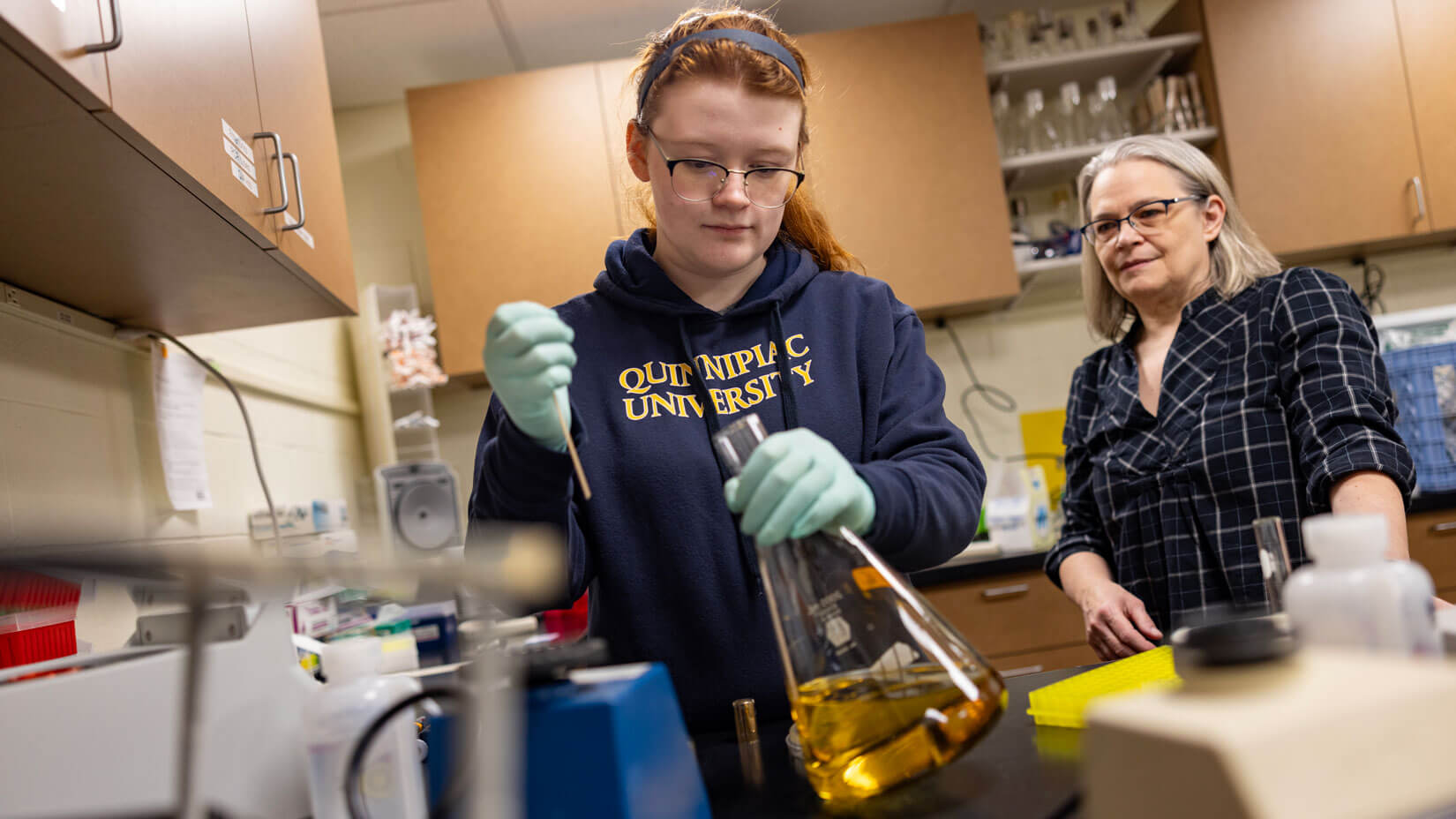 A student mixes a solution in a beaker during a lab experiment.