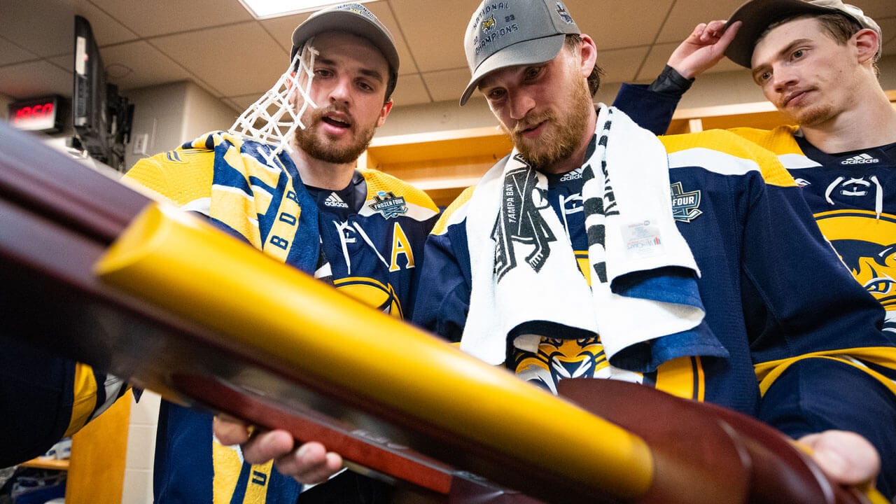 Quinnipiac ice hockey team admiring NCAA trophy