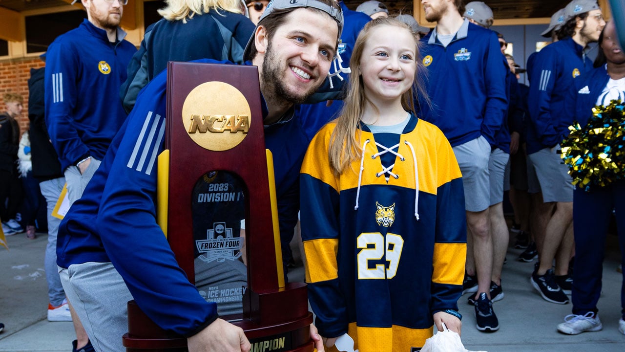 Teammate holding trophy taking photo with young fan