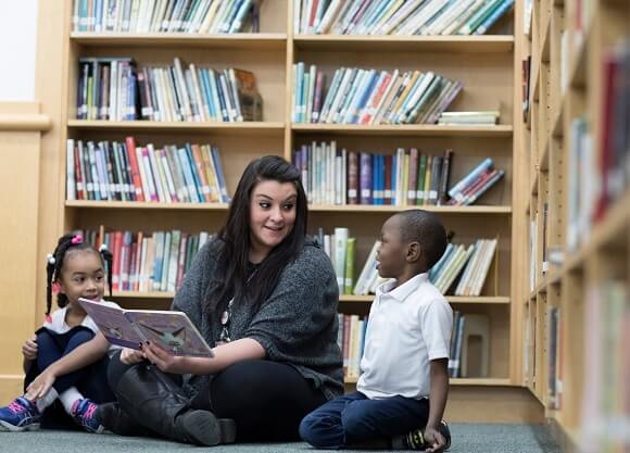 Marisa Laudano reads a children's book to two elementary students at Fair Haven School