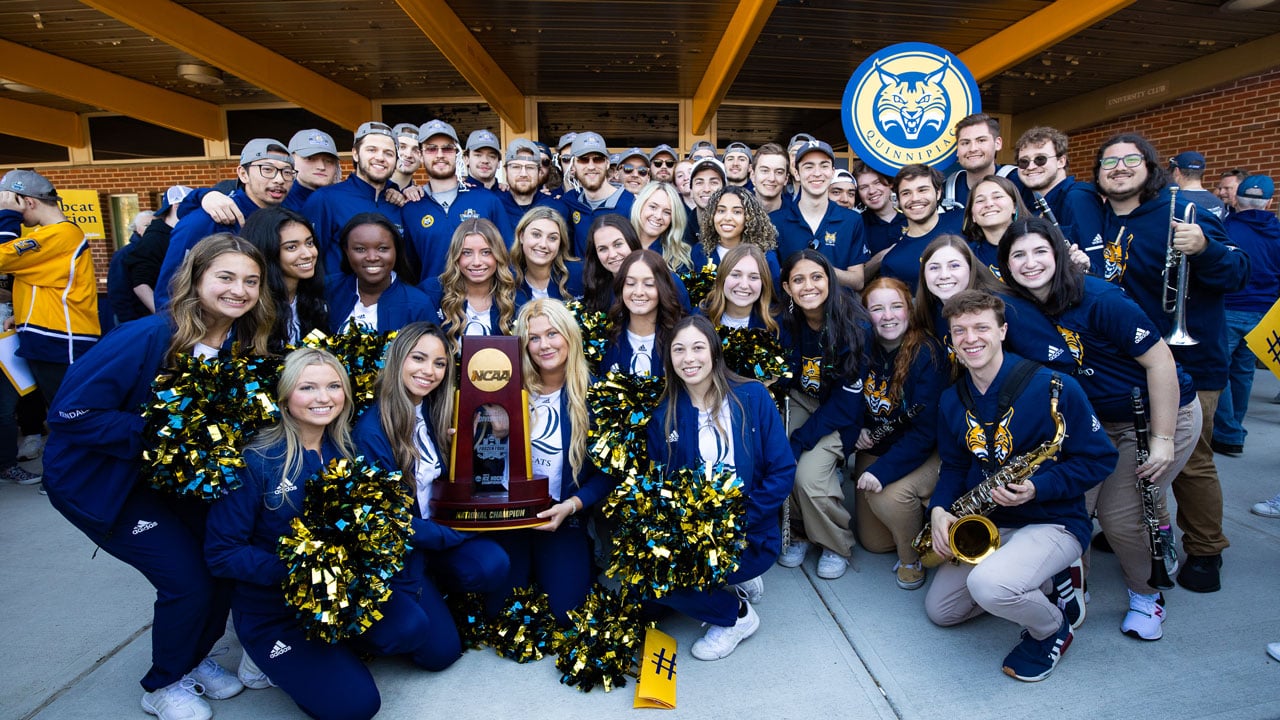 Ice cats, pep band, and hockey team take photo together