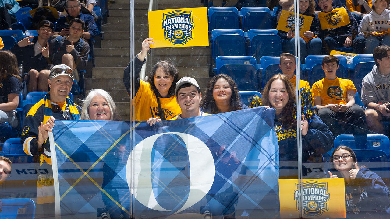 Smiling fans holding a Quinnipiac flag