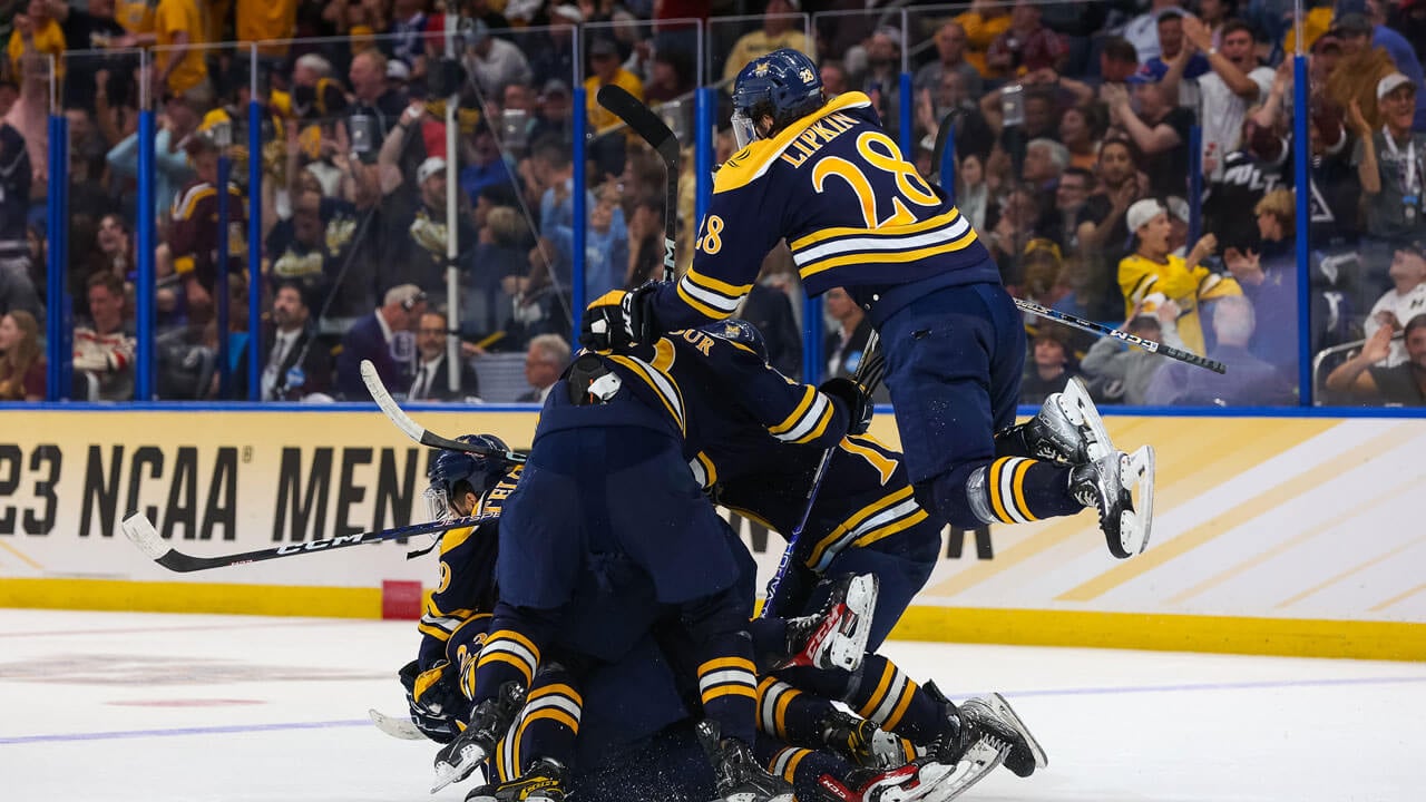 Ice hockey team piling on top of each other to celebrate