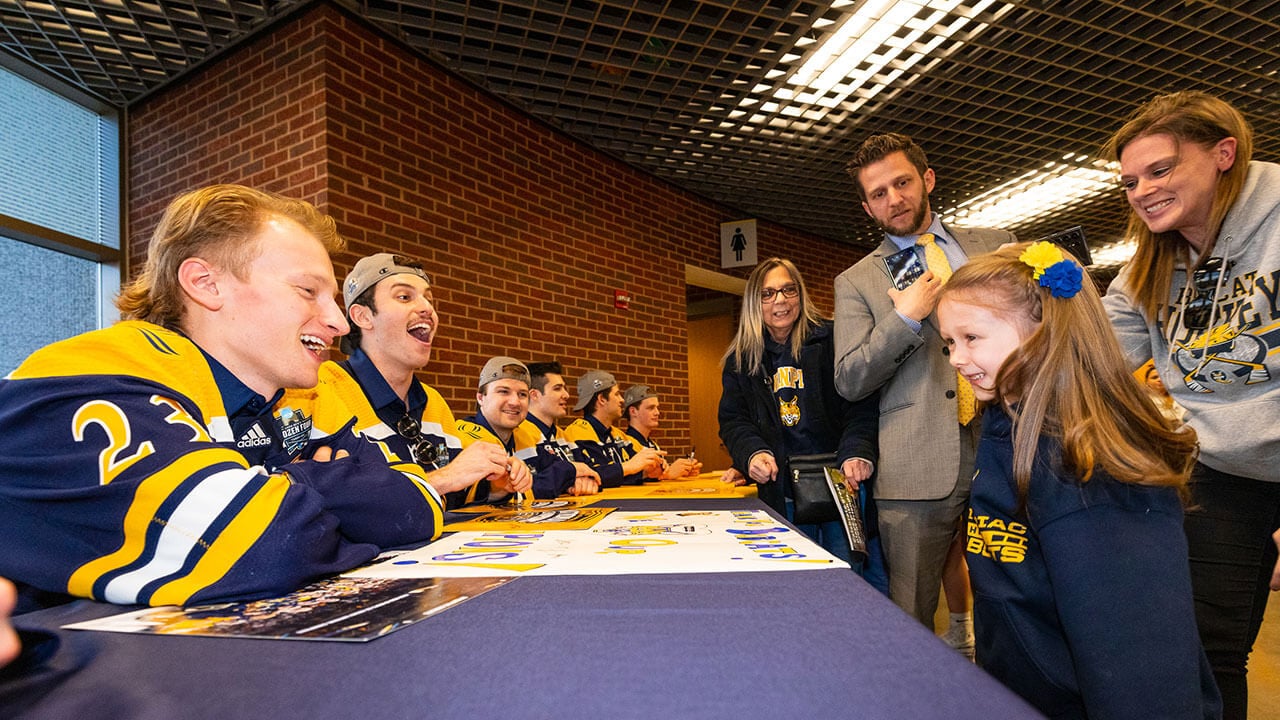 Fans line up smiling to congratulate the Quinnipiac mens ice hockey team