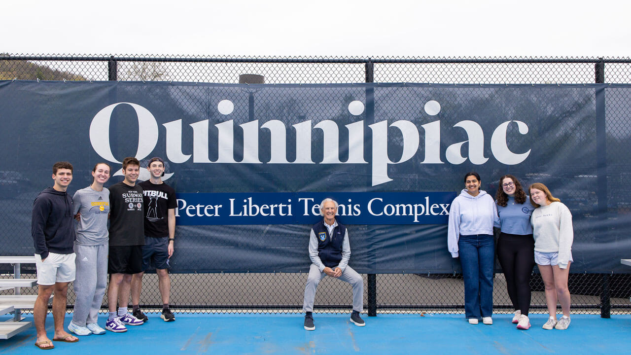 Peter Liberti smiles with student athletes in front of the new Peter Liberti tennis complex