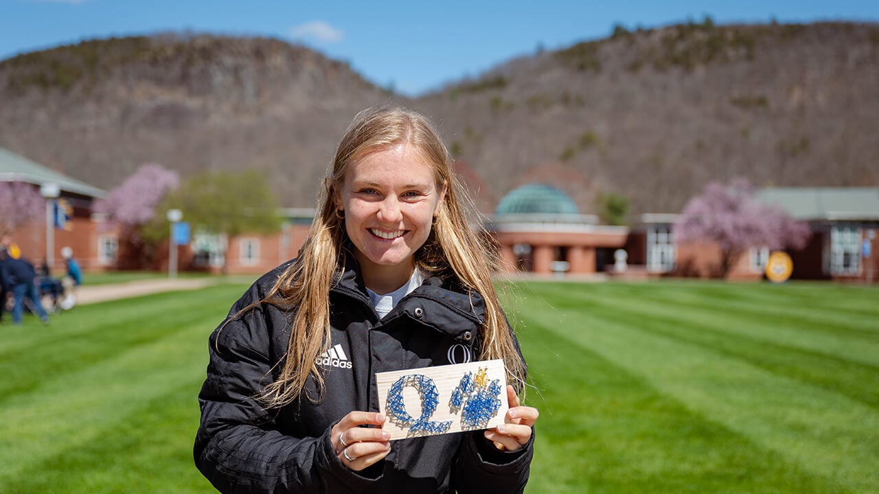 A student smiles in front of the mountain.