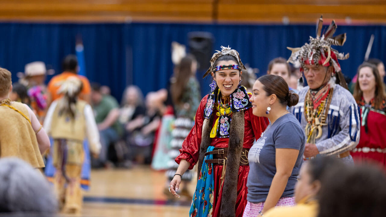 Participants at the Dancing in the Shadow of Sleeping Giant powwow walk across the gym