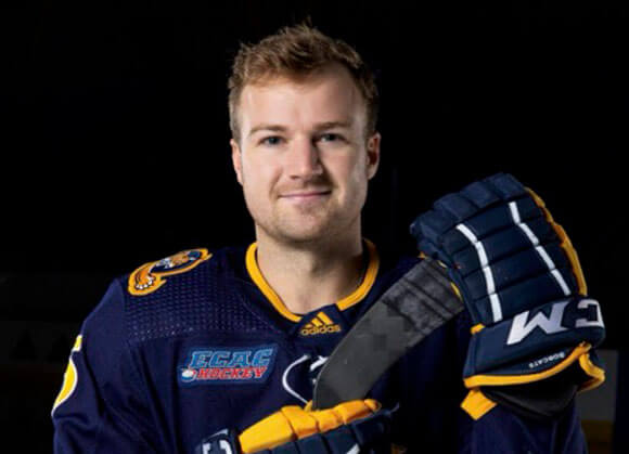 Student holds hockey stick and smiles for photo