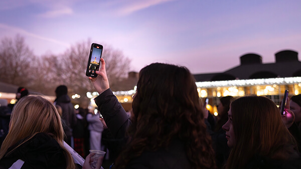 Student taking photo of the Arnold Bernhard Library during the annual Quad lighting