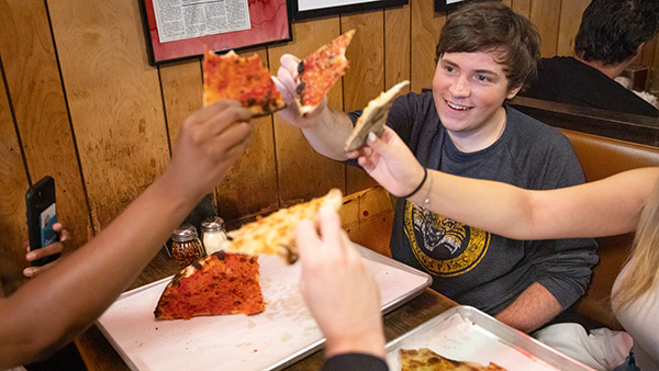 Students enjoying a pizza at a New Haven Pizza restaurant