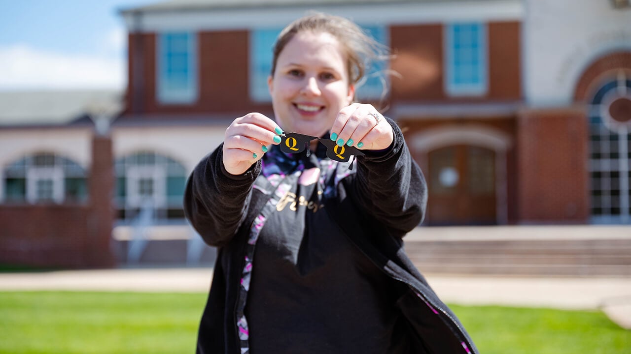 A student holds up two Q pins.