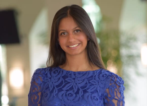 Sarah Almeida smiles in a blue shirt.