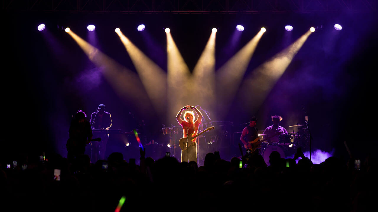 The Driver Era's Ross Lynch holds up a heart hand sign to the crowd under stage lights