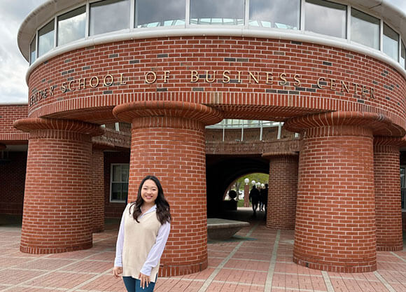 Rachel Sin smiling in front of the Lender School of Business building