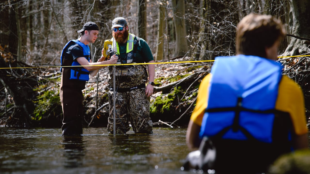 Civil engineering students measure streamflow with the USGS at the Mill River.