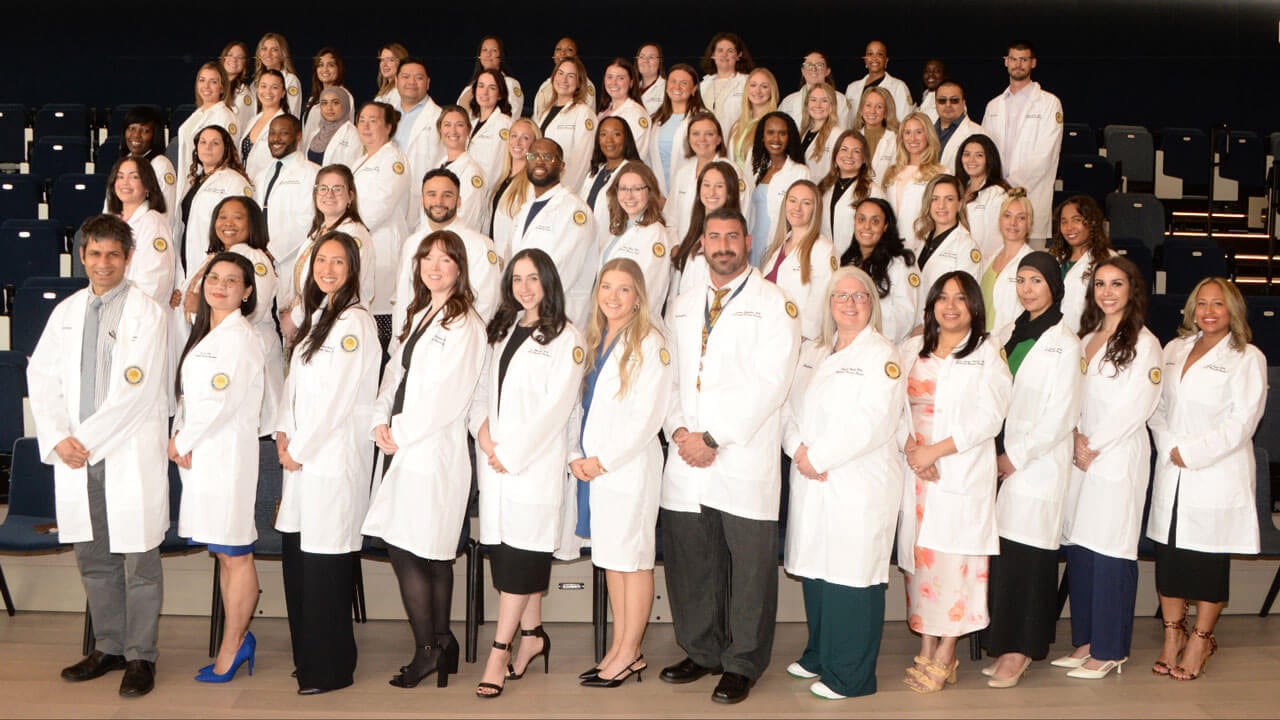 Students smile in their white coats at the School of Nursing’s white coat ceremony celebrating MSN Nurse Practitioners