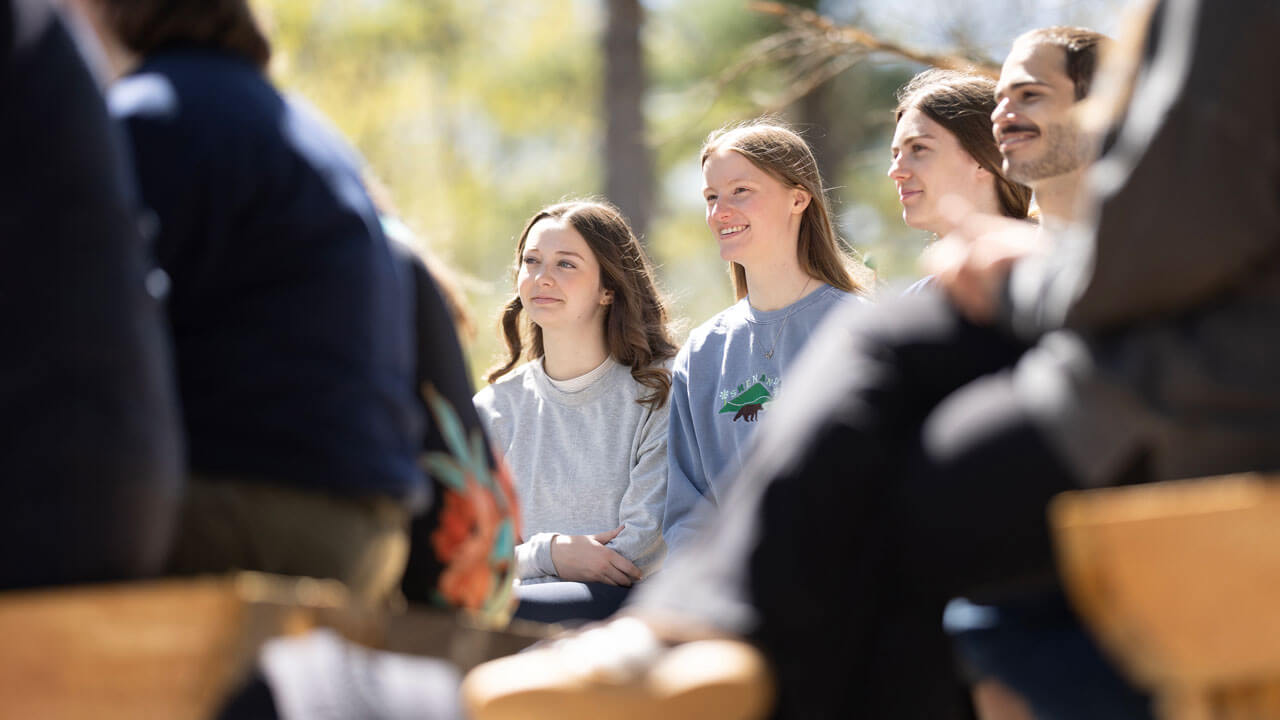 Students joyfully listen to their professor outside