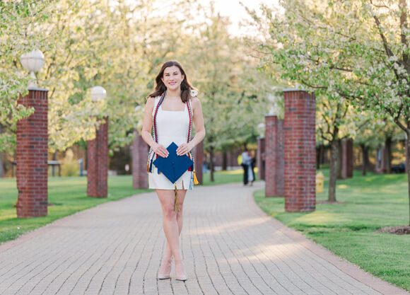 Jackie Ydrovo stands holding her graduation cap