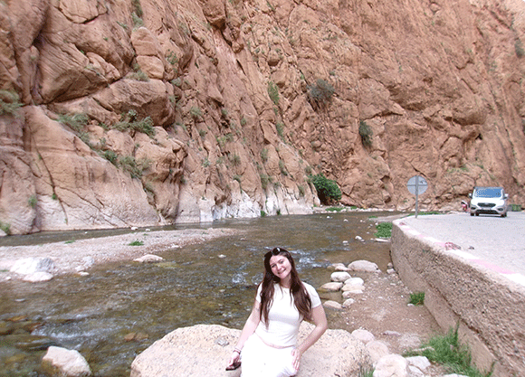 Student relaxes in front of water.