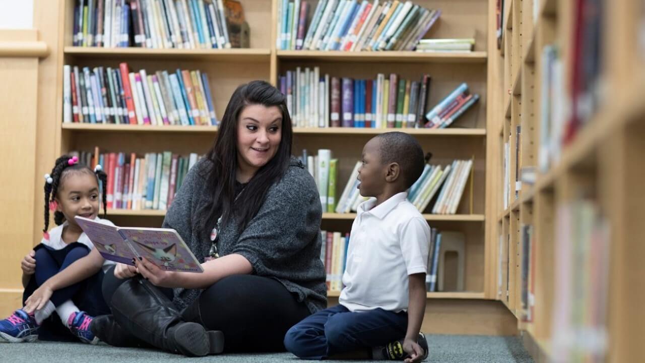 Marisa Laudano reads a children's book to two elementary students at Fair Haven School.