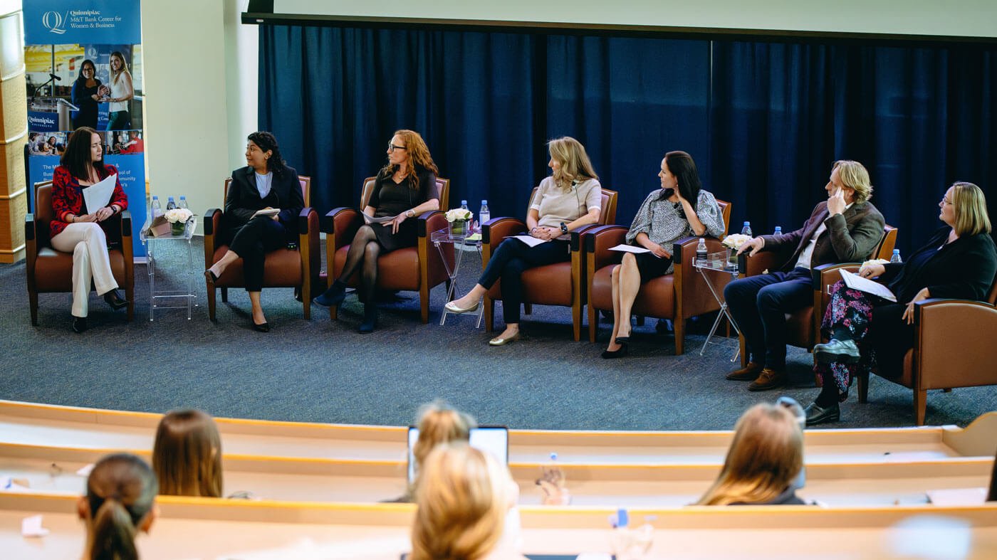 Faculty members participate in a panel in an auditorium.