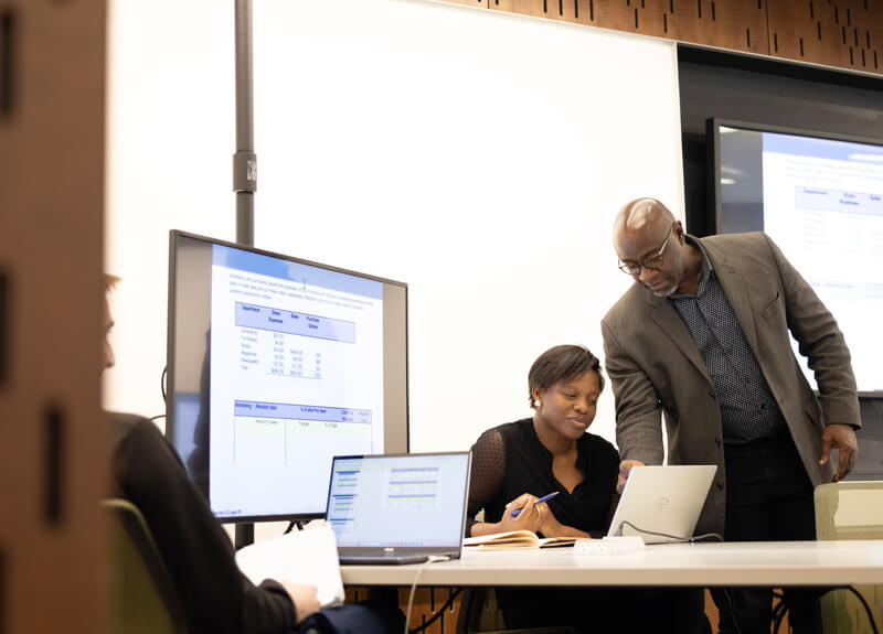 A professor instructs a graduate student during an accounting course.