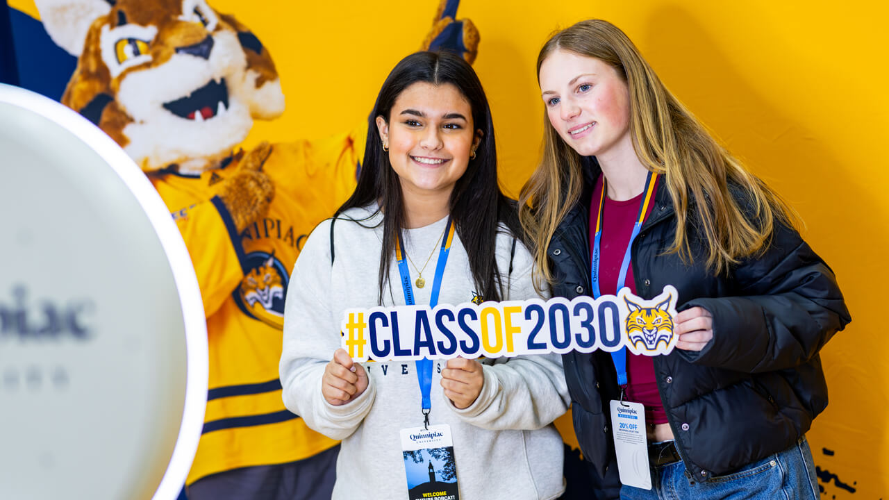Two admitted students smile for a photo holding a Class of 2030 sign