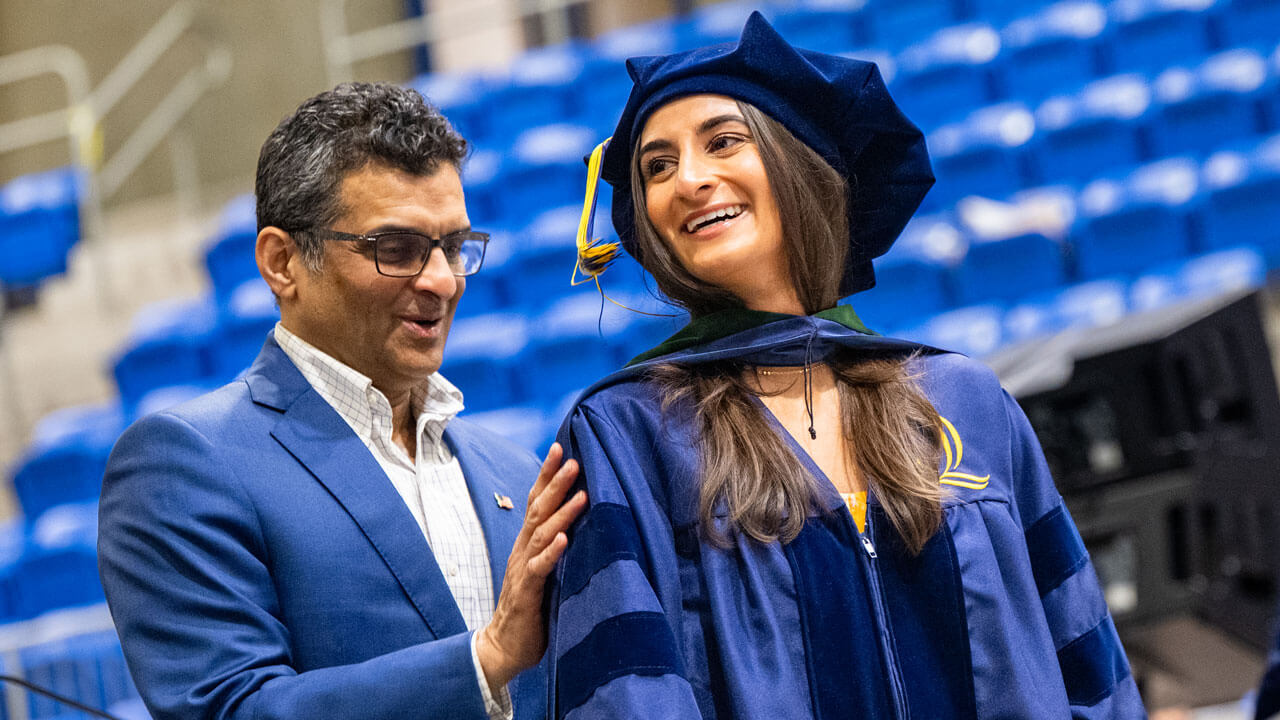 Guest looks lovingly at their student as they receive their hood.