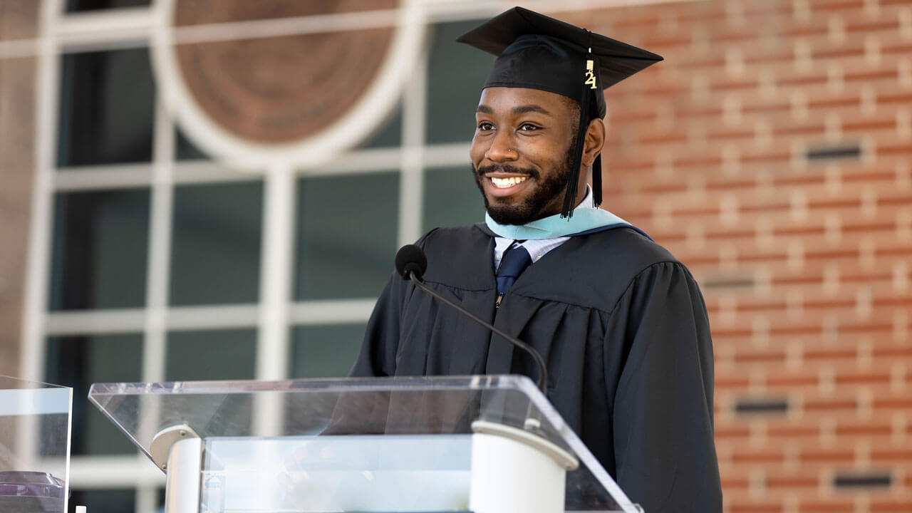 Da'Jhon Darren Jett speaks infront of podium to his fellow graduate class