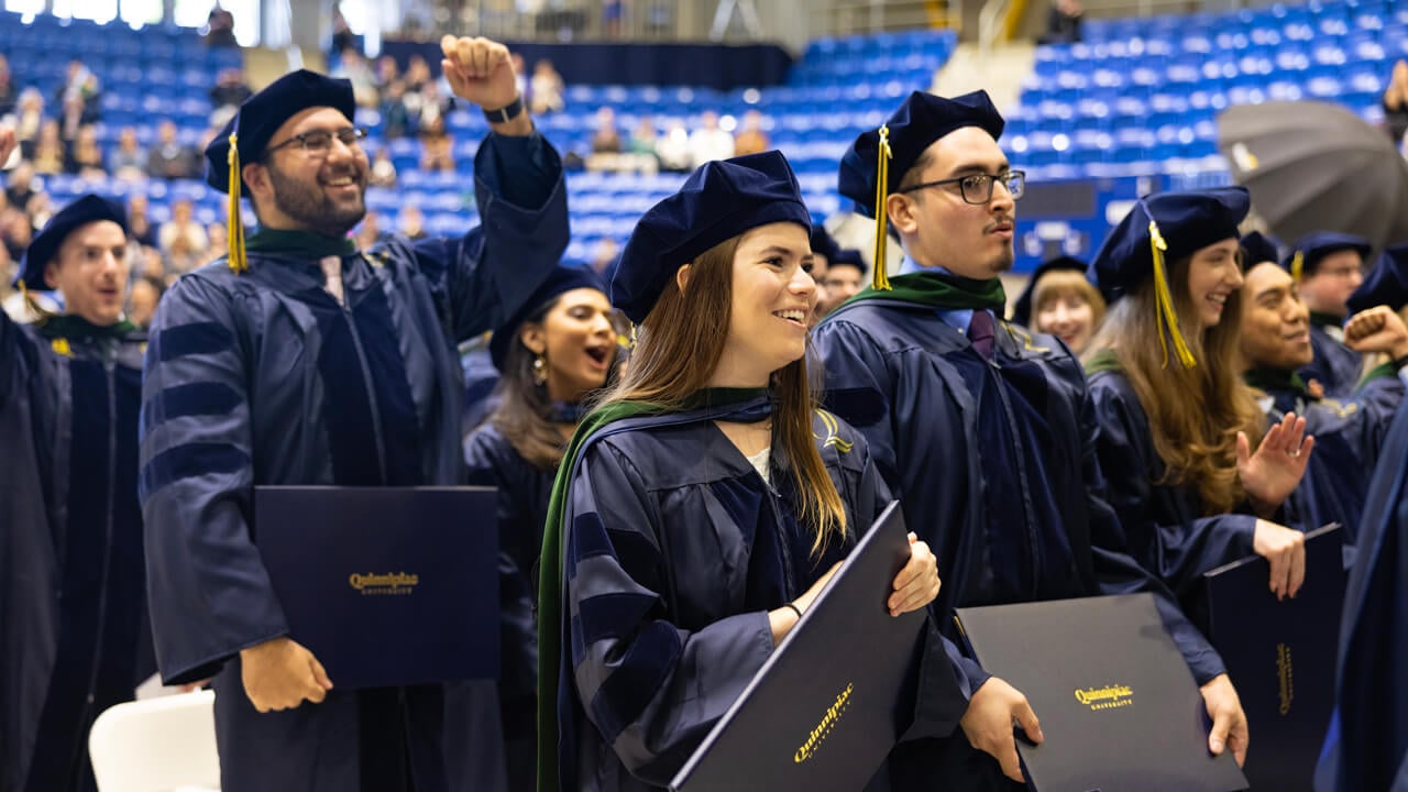 Dozens of graduates cheer and wave their arms