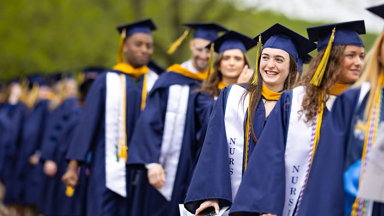 A student smiling as they process in for commencement