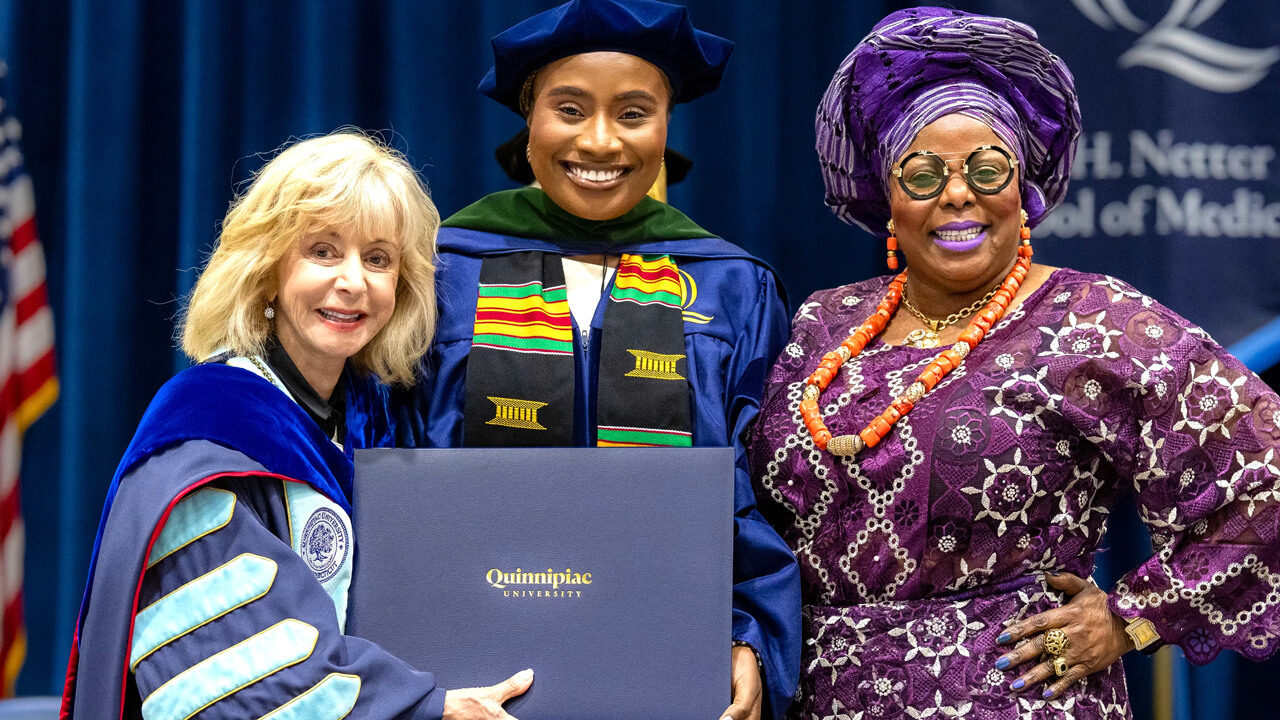 President Olian poses for a photo with a graduate and her loved one on the stage