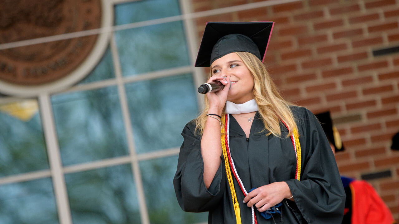 Heather Popovics sings with a microphone on the library steps