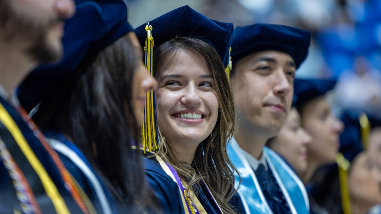 Class of 2024 law graduate sends a smile to someone in the audience.