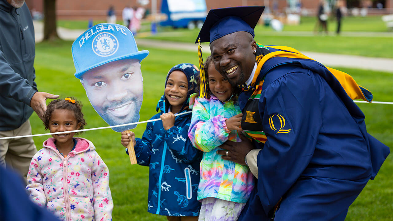 Graduating student poses with children.