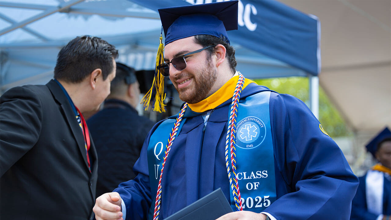 Male student in cap and gown with diploma.