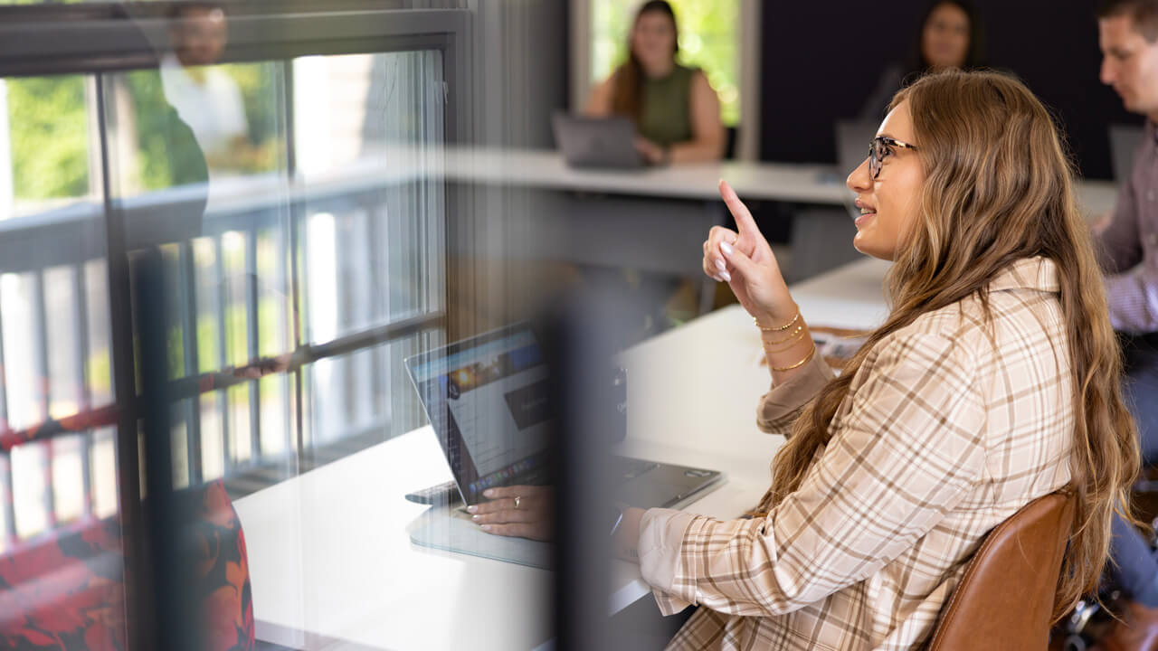 A woman sitting in a meeting, making a verbal point