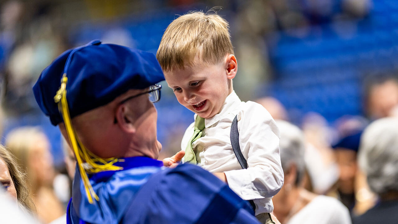 Graduate holds baby.