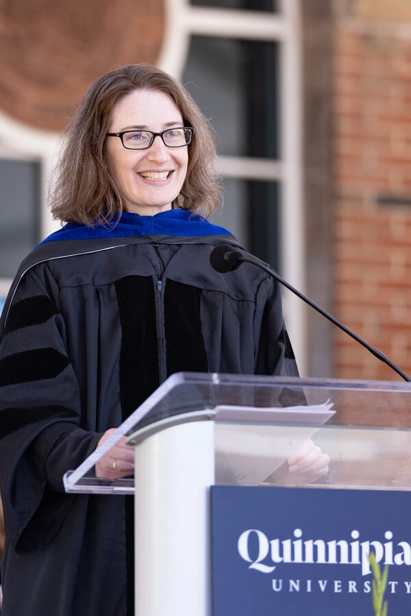 Adele Merritt, PhD, speaks from a podium on stage