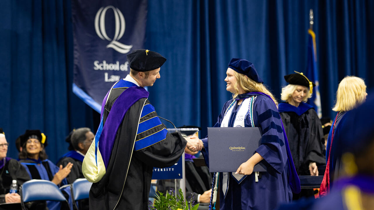 Graduate shakes hands with Dean Brian Gallini