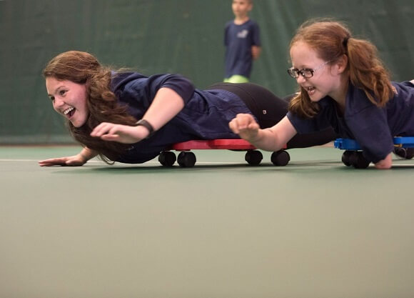 Quinnipiac graduate occupational therapy student and child play on scooter boards at camp.