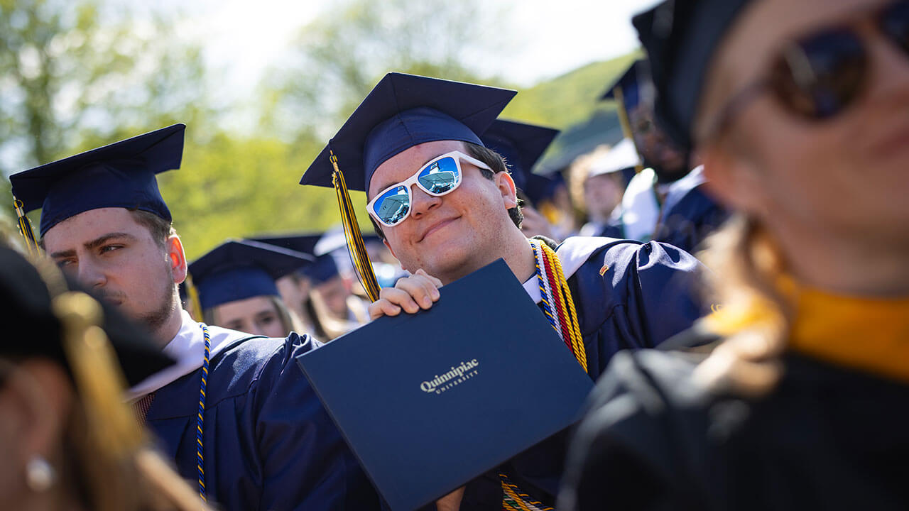 graduate poses with their new diploma