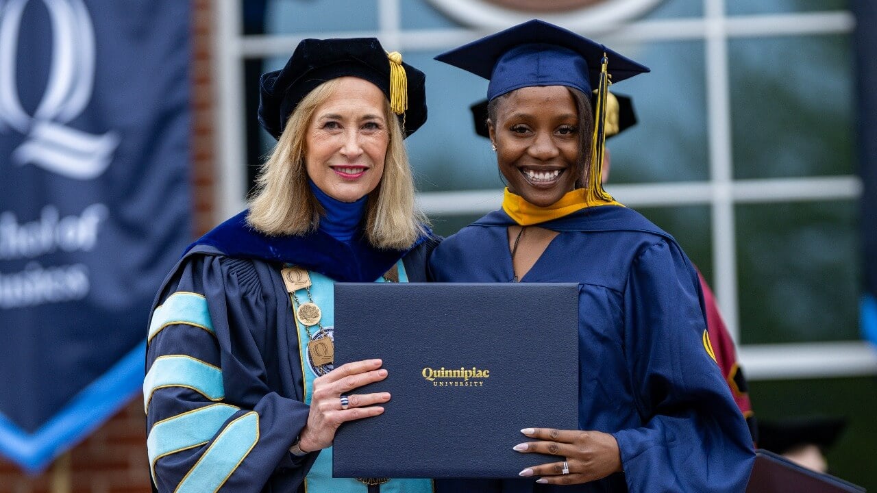 Graduate holds diploma next to President Hardin