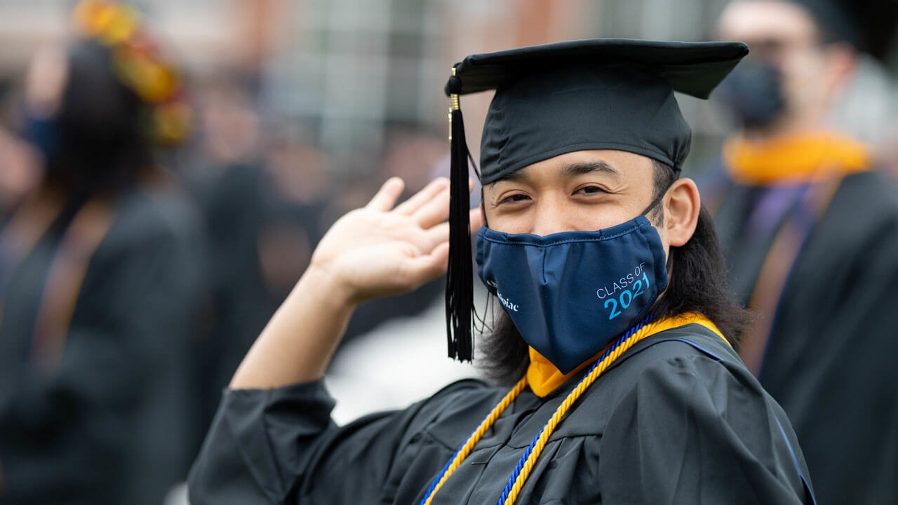 A graduate excitedly waves from his seat on the Quad